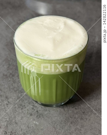 Matcha latte in a clear cup with vibrant green color, topped with creamy froth, highlighting smooth texture, swirling patterns, and refreshing appearance in close-up detail Matcha latte in a clear cup with vibrant green color, topped with creamy froth, highlighting smooth texture, swirling patterns, and refreshing appearance in close-up detail 142822116