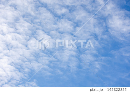 Soft blue sky filled with wispy altocumulus clouds forming a textured, airy background Soft blue sky filled with wispy altocumulus clouds forming a textured, airy background 142822825
