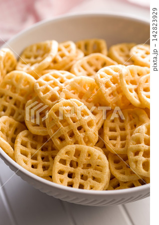 Bowl Of Crispy Waffle Potato Chips Snack Food In A White Bowl For Parties And Snacking 142823929