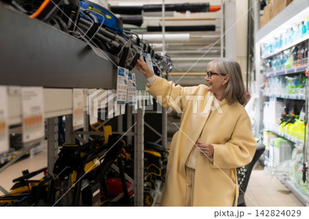 Happy senior woman choosing garden tools in a retail hardware store aisle 142824029