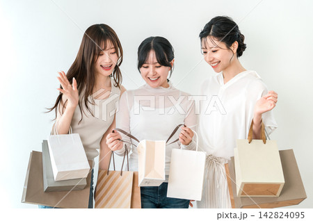 ショッピングバッグの中身を見て盛り上がる笑顔の女性たち ショッピングバッグの中身を見て盛り上がる笑顔の女性たち 142824095