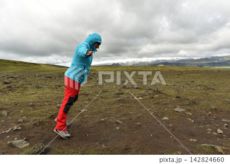 Hiker battling strong wind on a mountain plateau in Landmannalaugar Iceland Hiker battling strong wind on a mountain plateau in Landmannalaugar Iceland 142824660