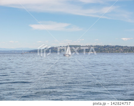 A solitary white sailboat drifting on the vast blue water of Puget Sound, Ruston, WA. A solitary white sailboat drifting on the vast blue water of Puget Sound, Ruston, WA. 142824757