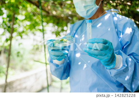 Scientist in protective gear recording crop health data on a clipboard in an outdoor agricultural 142825228