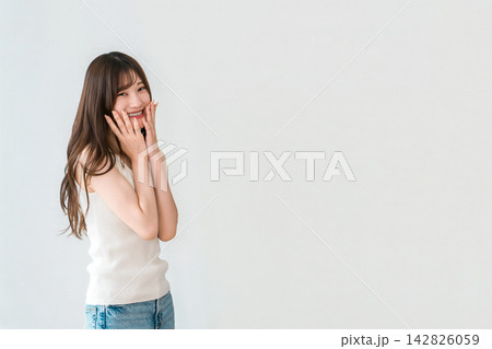 頬に手を添えて笑顔を見せる若い女性。美肌とスキンケアのビューティーイメージ 頬に手を添えて笑顔を見せる若い女性。美肌とスキンケアのビューティーイメージ 142826059