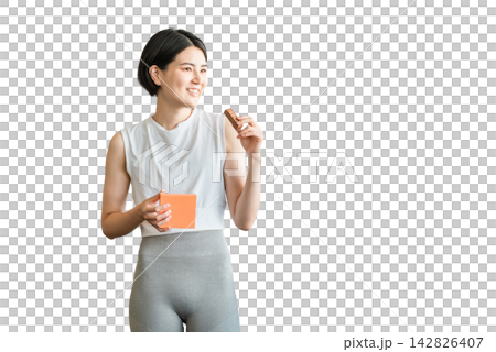 Young Asian woman in yoga wear eating a protein/nutrition bar Young Asian woman in yoga wear eating a protein/nutrition bar 142826407