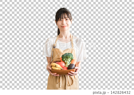 Asian woman in an apron, housewife, holding vegetables. 142826432