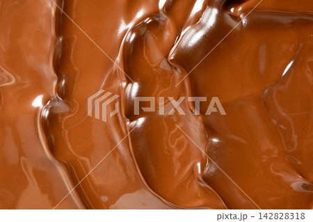 Swirling melted milk chocolate background with glossy wave texture Swirling melted milk chocolate background with glossy wave texture 142828318