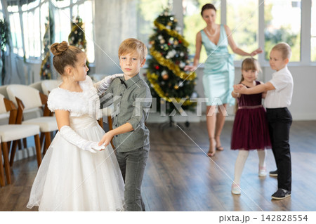 Christmas ball - group of preteen children in festive clothes dances a foxtrot near New Year tree 142828554