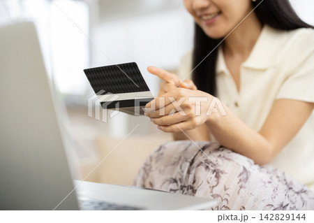 通帳を見ながら微笑む若い女性の手元のクローズアップ 通帳を見ながら微笑む若い女性の手元のクローズアップ 142829144