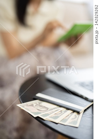 テーブルの上に乗った通帳と一万円札のクローズアップ 142829262