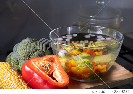 Cooling blanched vegetables in ice water on a kitchen counter with colorful produce Cooling blanched vegetables in ice water on a kitchen counter with colorful produce 142829286