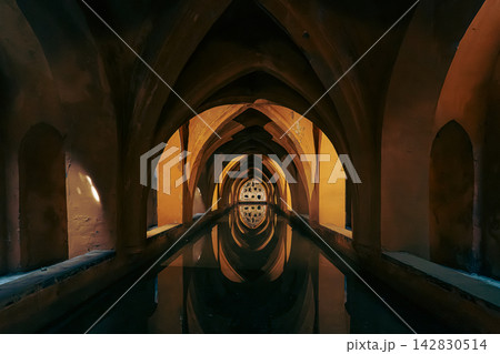 Golden light illuminates vaulted arches reflecting in the underground baths of the Real Alcazar Golden light illuminates vaulted arches reflecting in the underground baths of the Real Alcazar 142830514