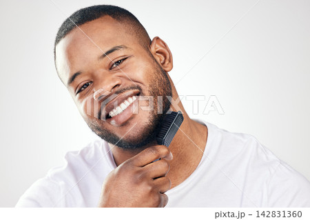 Black man, portrait and beard brush in studio for hair grooming or healthy hygiene, white background or self care. Male person, face and comb tool or morning routine for beauty, maintenance or smile 142831360