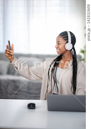 Young adult woman taking selfie with headphones and phone Young adult woman taking selfie with headphones and phone 142832609