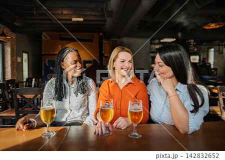 Diverse women friends enjoying beer in pub Diverse women friends enjoying beer in pub 142832652