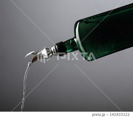 Antique dark green glass bottle with vintage pourer on a gray background. Antique dark green glass bottle with vintage pourer on a gray background. 142833122