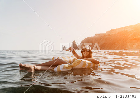 Woman, Beach, Float, Relaxing on Inflatable Raft in Ocean near Rocky Coastline Woman, Beach, Float, Relaxing on Inflatable Raft in Ocean near Rocky Coastline 142833403