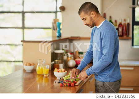 Cooking, man and cutting fruits for breakfast, nutrition or hungry for natural healthy diet in home kitchen. Morning, knife and chopping board for food, organic salad and meal prep with ingredients 142833550