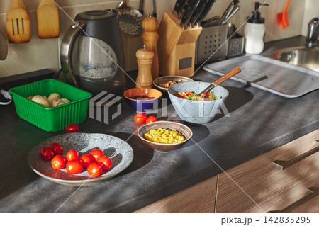 Sunliht modern kitchen with plate of quinoa filled with vegetables and ingredients on the countertop. 142835295