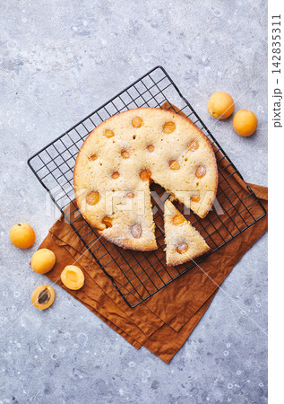 Delicious homemade apricot pie with fresh apricots on baking grid on gray background with napkin. Summer fruit pie. Delicious homemade apricot pie with fresh apricots on baking grid on gray background with napkin. Summer fruit pie. 142835311
