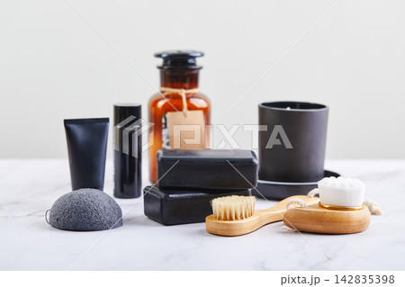 Three pieces of black charcoal soap, Konjac sponge, beauty care products, candles and brushes for washing and massage on marble background 142835398