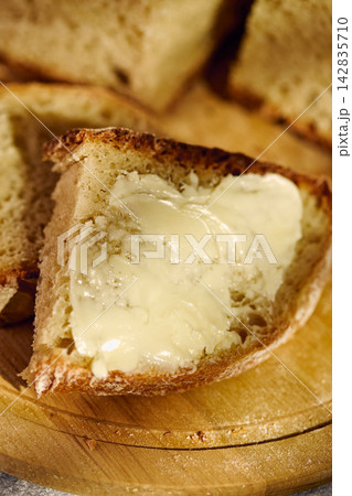 Fresh rustic bread slice with butter on wooden cutting board Fresh rustic bread slice with butter on wooden cutting board 142835710