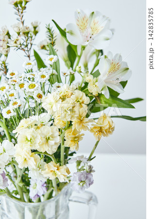 Mixed bouquet of purple, white and yellow flowers in a glass jug 142835785