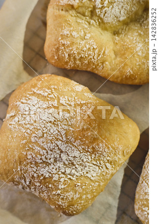 Close-up of homemade mini ciabatta rolls dusted with flour on parchment paper 142836252