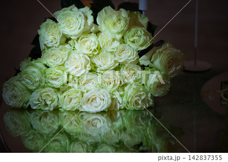 White roses arranged on a reflective surface in a dimly lit space during a special occasion 142837355