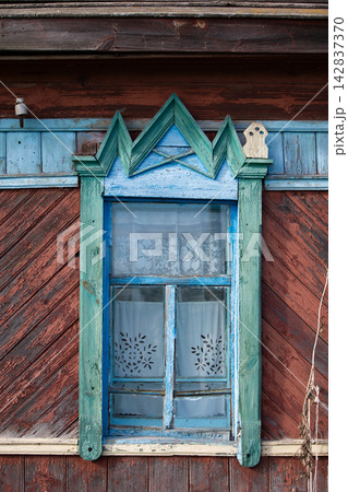 Wooden window with blue frame and patterned curtains on a rustic house in a rural area during daylight Wooden window with blue frame and patterned curtains on a rustic house in a rural area during daylight 142837370