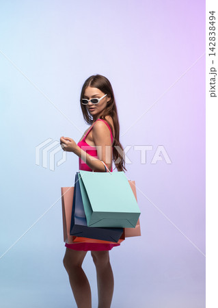 Woman fashionably dressed, holding multiple shopping bags, posing stylishly after a successful shopping spree Woman fashionably dressed, holding multiple shopping bags, posing stylishly after a successful shopping spree 142838494