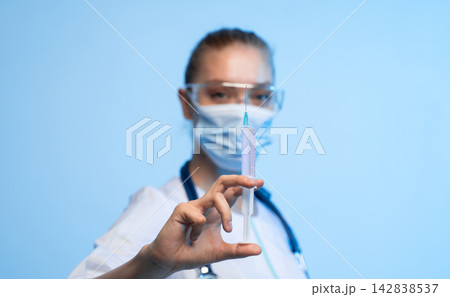 Healthcare worker holding a syringe with medicine, ready for injection, representing vaccination and medical treatment 142838537