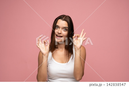 Joyful young woman flashing the okay sign with both hands, showing her agreement, approval, and optimism Joyful young woman flashing the okay sign with both hands, showing her agreement, approval, and optimism 142838547
