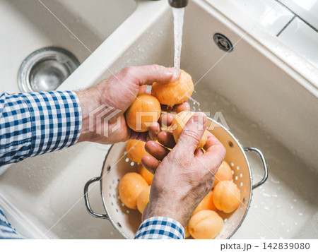 Male hands wash ripe apricots Male hands wash ripe apricots 142839080