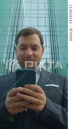 Vertical video. Young Professional Using Smartphone Near Business Center. Vertical video. Young Professional Using Smartphone Near Business Center. 142839217
