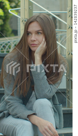 Vertical video. Businesswoman sitting on stairs near office center with carton box and documents with a table flower as lost job. Female office worker in despair lost job. Unemployment rate growing Vertical video. Businesswoman sitting on stairs near office center with carton box and documents with a table flower as lost job. Female office worker in despair lost job. Unemployment rate growing 142839237