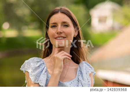 Pretty young beaming woman in a light dress in the park 142839368