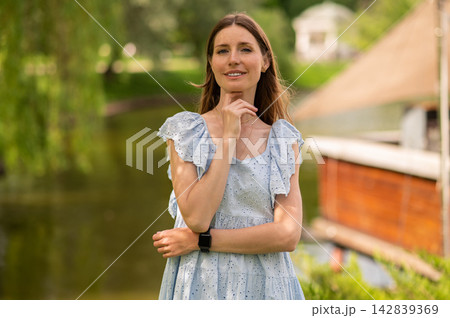 Pretty young beaming woman in a light dress in the park 142839369