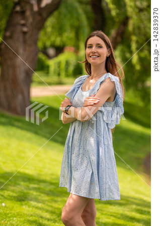 Pretty young beaming woman in a light dress in the park 142839370
