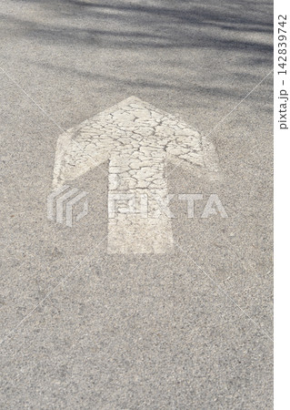 Weathered white arrow road marking on grey asphalt 142839742