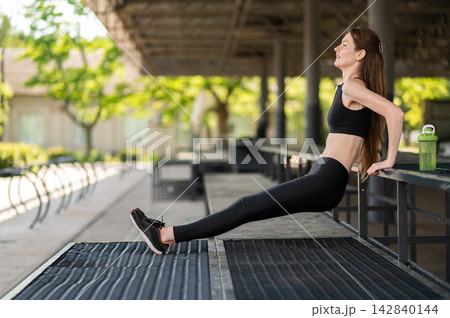 Fit young woman doing back push ups and looking focused and involved 142840144