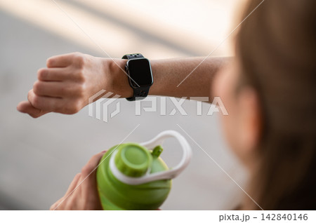 Close up of the female hand with watches and green bottle for water 142840146