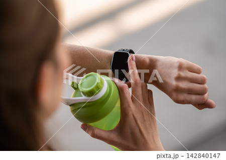 Close up of the female hand with watches and green bottle for water Close up of the female hand with watches and green bottle for water 142840147