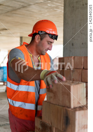 Specialist stacks bricks in area during work process 142840165