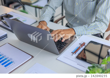 Professional financial analyst working on laptop with charts and calculator in modern office. Professional financial analyst working on laptop with charts and calculator in modern office. 142840235