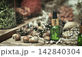 A green glass bottle of natural essential oil among acorns, pinecones and dry herbs on wooden surface, authentic organic extract, selected focus. 142840304