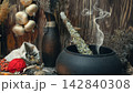Pagan witch magic altar. Smoking twist of bitter wormwood herb for fumigation in cast iron cauldron, ritual objects in wooden background, dark key, selective focus. 142840308