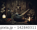 Authentic forest witch altar. Burning candles, dry herbs, iron cauldron, smoking mugwort, bulls skull mojo, bunch of garlic in wooden background in the dark, low key, selective focus. 142840311