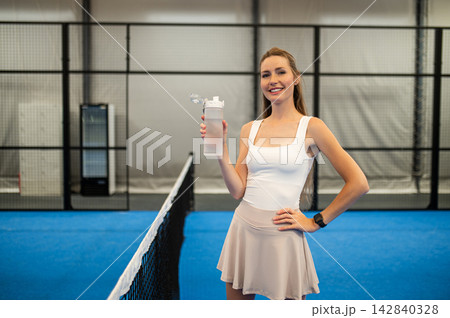 Cute caucasian young woman at paddle tennis court with a bottle of water in hands 142840328